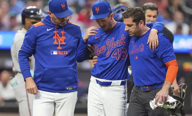 New York Mets pitcher Griffin Canning, center, is helped off the field by head athletic trainer Joseph Golia, right, and pitching coach Jeremy Hefner during the third inning of a baseball game against the Atlanta Braves Thursday, June 26, 2025, in New York. (AP Photo/Frank Franklin II)