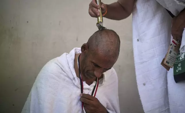 A Muslim pilgrim shaves his head, a significant part of the Umrah and Hajj rituals in Islam, during the symbolic stoning of the devil, the last rite of the annual Hajj, in Mina near the holy city of Mecca, Saudi Arabia, Friday, June 6, 2025. (AP Photo/Amr Nabil)