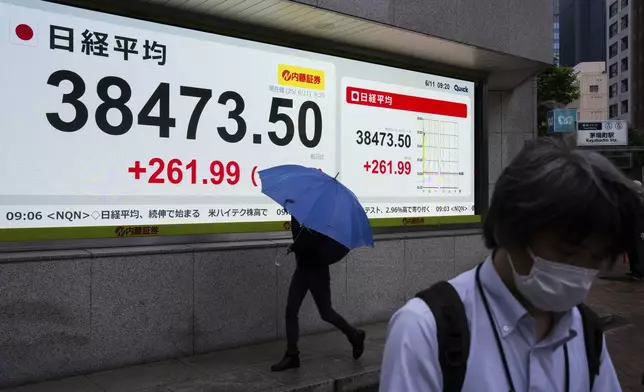 Pedestrians pass by an electronic stock board showing Japan's Nikkei index at a securities firm in Tokyo, Wednesday, June 11, 2025. (AP Photo/Louise Delmotte)