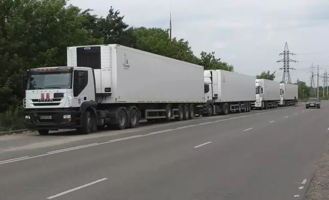 In this photo, taken from video distributed by Russian Defense Ministry Press Service on Sunday, June 8, 2025, the motorcade of refrigerators of the first convoy carrying bodies of Ukrainian soldiers for repatriation is parked at an exchange area near Novaya Guta, Belarus, for the beginning of a large-scale exchange between Russia and Ukraine. (Russian Defense Ministry Press Service via AP)