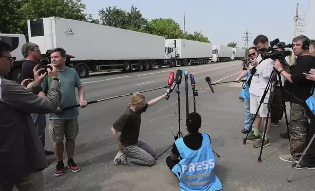 In this photo, taken from video distributed by Russian Defense Ministry Press Service on Sunday, June 8, 2025, Journalists gather near the motorcade of refrigerators of the first convoy carrying bodies of Ukrainian soldiers for repatriation at an exchange area near Novaya Guta, Belarus, for the beginning of a large-scale exchange between Russia and Ukraine. (Russian Defense Ministry Press Service via AP)