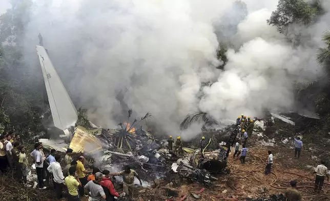 FILE - Civilians look on as Indian firefighters and rescue personnel work on the site of an Air India plane that crashed in Mangalore, in the southern Indian state of Karnataka, Saturday, May 22, 2010. (AP Photo, File)