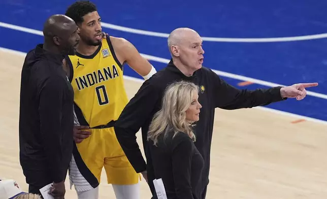 Indiana Pacers head coach Rick Carlisle, right, motions to players on the court as assistant coach Lloyd Pierce, far left, talks with guard Tyrese Haliburton (0) during the third quarter of Game 5 of the NBA basketball Eastern Conference finals against the New York Knicks, Thursday, May 29, 2025, in New York. (AP Photo/Frank Franklin II)