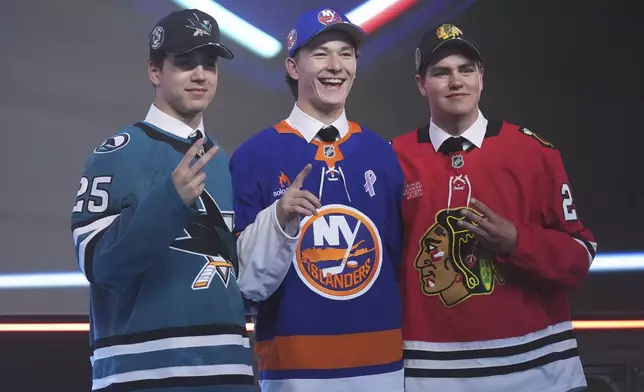 Matthew Schaefer, drafted first by the New York Islanders, middle, stands between Michael Misa, drafted second by the San Jose Sharks, left, and Anton Frondell, drafted third by the Chicago Blackhawks, during the NHL hockey draft Friday, June 27, 2025, in Los Angeles. (AP Photo/Damian Dovarganes)
