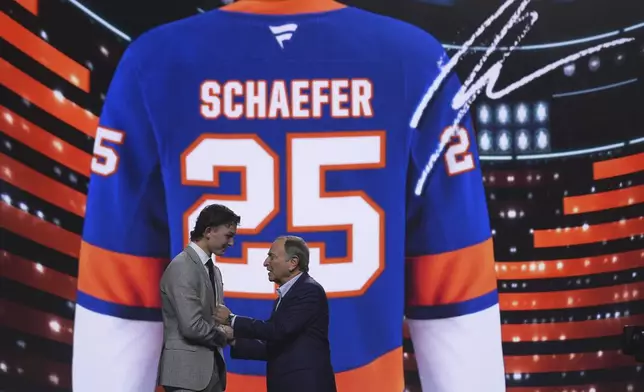 Matthew Schaefer, left, stands with NHL commissioner Gary Bettman after being drafted by the New York Islanders during the NHL hockey draft Friday, June 27, 2025, in Los Angeles. (AP Photo/Damian Dovarganes)