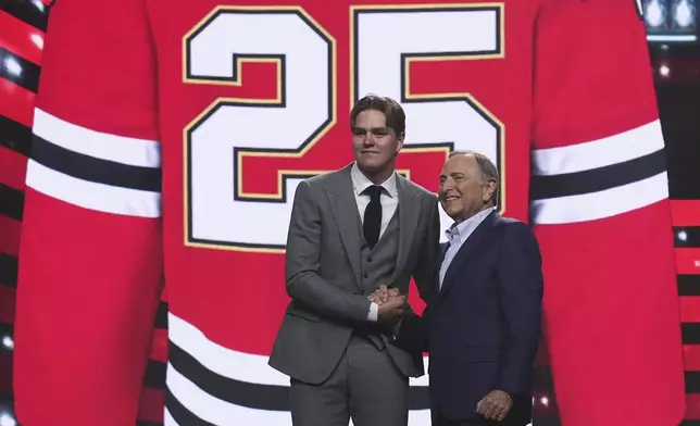 Anton Frondell, left, is congratulated by NHL commissioner Gary Bettman after being drafted by the Chicago Blackhawks during the NHL hockey draft Friday, June 27, 2025, in Los Angeles. (AP Photo/Damian Dovarganes)