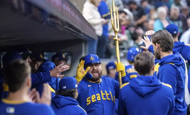 Seattle Mariners' Rowdy Tellez, center, celebrates in the dugout after hitting a solo home run during the fourth inning of a baseball game against the Cleveland Guardians, Friday, June 13, 2025, in Seattle. (AP Photo/Stephen Brashear)