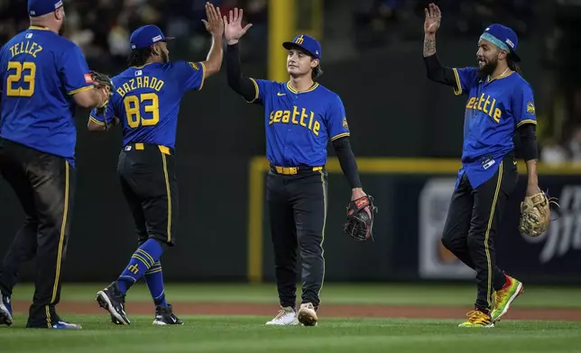Seattle Mariners, from left, Rowdy Tellez, Eduard Bazardo., Cole Young and J.P. Crawford celebrate after a baseball game against the Cleveland Guardians, Friday, June 13, 2025, in Seattle. (AP Photo/Stephen Brashear)