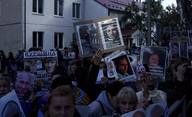 People hold photos of their missed relatives as Ukrainian soldiers return from captivity during a POWs exchange between Russia and Ukraine, in Chernyhiv region, Ukraine, Thursday, June 26, 2025. (AP Photo/Evgeniy Maloletka)