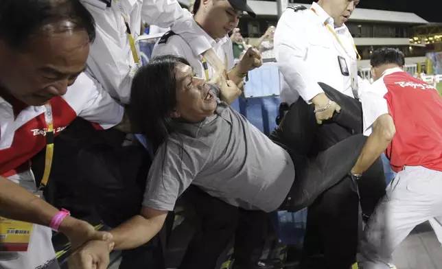 FILE - Security guards force to take away Pro-democracy protesters, Hong Kong legislator Leung Kwok-hung, also known as nickname "Long Hair", on the spectator stand during the first day of Beijing Olympics Equestrian game in Hong Kong on Aug. 9, 2008 while demanding for human rights and to stop one party ruling in China. (AP Photo/Kin Cheung, File)