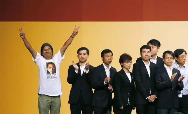 FILE - Leung Kwok-hung, also known as "Long Hair," left, of the pro-democracy League of Social Democrats celebrates after winning a seat on the Legislative Council next to Chan Hak-kan, second from right, of the pro-Beijing Democratic Alliance for the Betterment of Hong Kong Party in Hong Kong, on Sept. 10, 2012. (AP Photo/Kin Cheung, File)