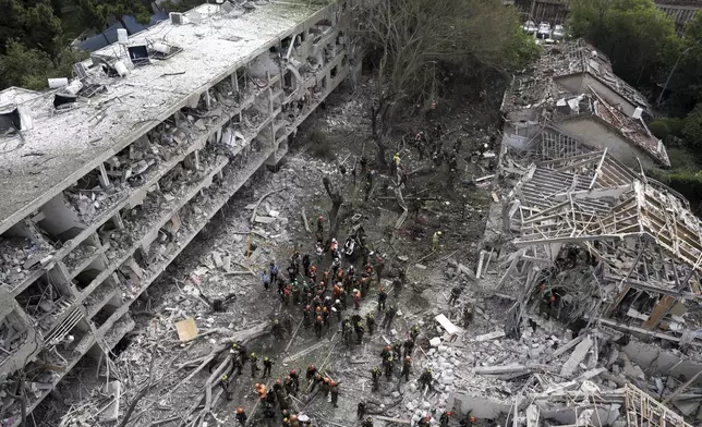 Rescue workers and firefighters survey the site of a direct missile strike launched from Iran in Tel Aviv, Israel, on Sunday, June 22, 2025. (AP Photo/Oded Balilty)