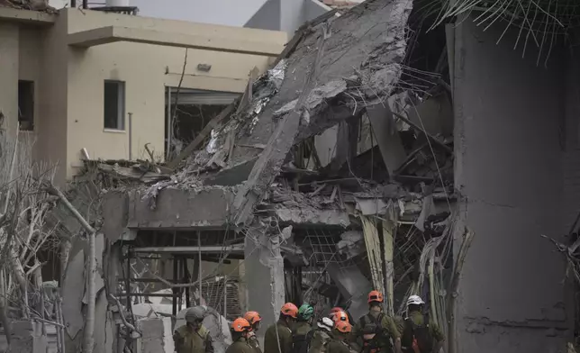 Israel's home front command officers survey the site where a missile launched from Iran struck in Nes Ziona ,Israel, Sunday, June 22, 2025. (AP Photo/Ohad Zwigenberg)