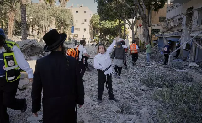 Rescue workers and residents react at the site where a missile launched from Iran struck in Haifa, Israel, Sunday, June 22, 2025. (AP Photo/Baz Ratner)