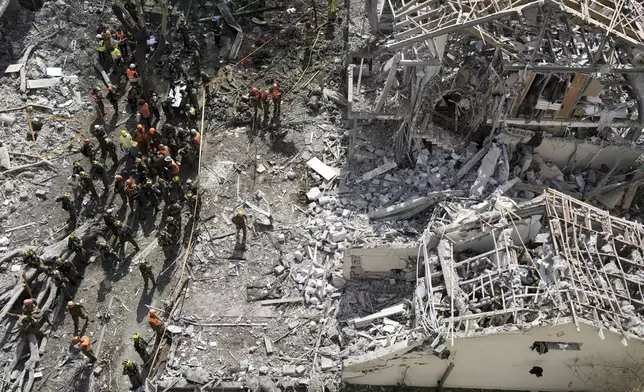 Firefighters, rescue workers and military gather at the site of a direct missile strike launched from Iran in Tel Aviv, Israel, on Sunday, June 22, 2025. (AP Photo/Oded Balilty)