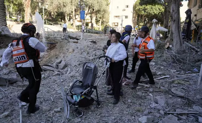 Rescue workers evacuate residents from the site where a missile launched from Iran struck in Haifa, Israel, Sunday, June 22, 2025. (AP Photo/Baz Ratner)