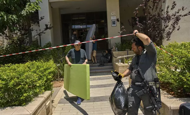 An Israeli border police officer helps residents to evacuate from a building damaged in an Iranian missile strike in Tel Aviv, Israel, Sunday, June 22, 2025. (AP Photo/Bernat Armangue)