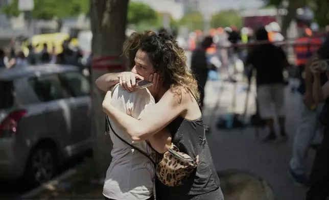 People react next to the site of a direct missile strike launched from Iran in Tel Aviv, Israel, on Sunday, June 22, 2025. (AP Photo/Bernat Armangue)