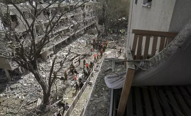 Israel's home front command officers and rescue workers survey the site of a direct missile strike launched from Iran in Tel Aviv, Israel, Sunday, June 22, 2025. (AP Photo/Oded Balilty)