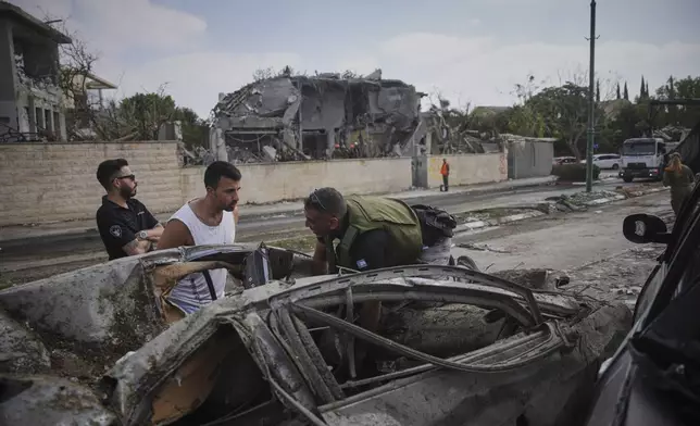 Rescue workers and firefighters survey the site of a direct missile strike launched from Iran in Nes Ziona ,Israel, Sunday, June 22, 2025. (AP Photo/Ohad Zwigenberg)