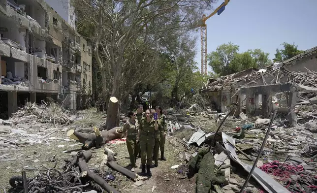 Israeli soldiers inspect the site struck by a direct missile strike launched from Iran in Tel Aviv, Israel, on Sunday, June 22, 2025. (AP Photo/Bernat Armangue)