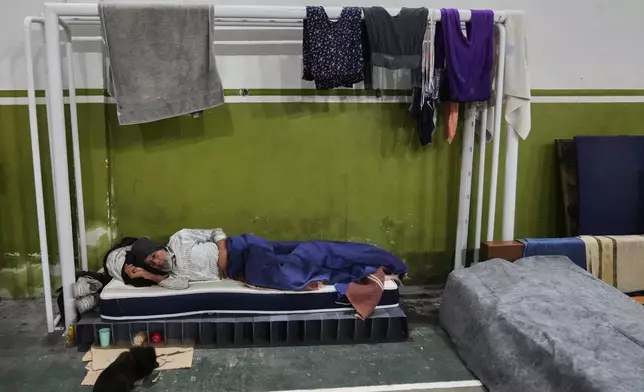 A person rests on a mattress at a gymnasium the government is using as a makeshift shelter in an effort to protect people without homes from cold weather in Montevideo, Uruguay, Wednesday, June 25, 2025. (AP Photo/Matilde Campodonico)