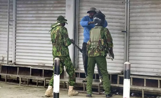 ADDS NAME: Kenyan police speak to vendor Boniface Kariuki before one of the policemen, left, shot him during a protest in Nairobi, Tuesday, June 17, 2025. (AP Photo/Brian Inganga)