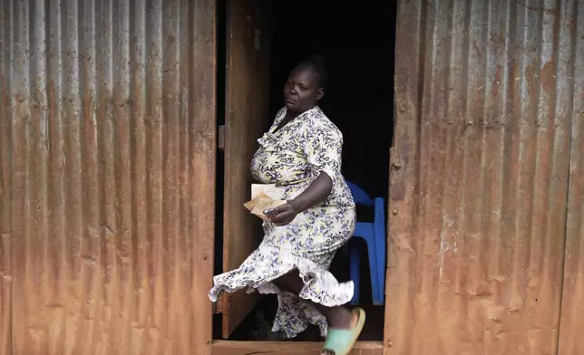 Susan Njeri, 44 years old, whose son Boniface Kariuki was shot at close range by a Kenyan police officer during a protest, walks out of her house in Muranga, Kenya, Wednesday, June 18, 2025. (AP Photo/Brian Inganga)