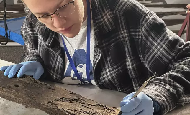 Research assistant Marissa Agerton cleans a piece of wood from a Revolutionary War-era gunboat to prepare for the craft's partial reconstruction at the New York State Museum, Friday, May 30, 2025, in Albany, New York. (AP Photo/Michael Hill)