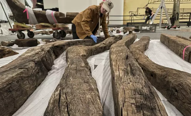 Research assistant Alyssa Carpenter inspects timbers from of a wooden Revolutionary War-era gunboat to prepare for the craft's partial reconstruction at the New York State Museum, Friday, May 30, 2025, in Albany, New York (AP Photo/Michael Hill)