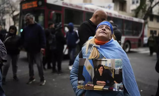 Norma Rivas, a supporter of former President Cristina Fernandez, holds a photo of the former president outside Fernandez's home after the nation's Supreme Court upheld her corruption conviction in Buenos Aires, Argentina, Tuesday, June 17, 2025. (AP Photo/Natacha Pisarenko)