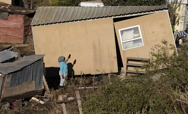 A woman takes a photograph of her damaged house, after floods swept through the area in Mthatha, South Africa, Thursday, June 12, 2025. (AP Photo/Themba Hadebe)