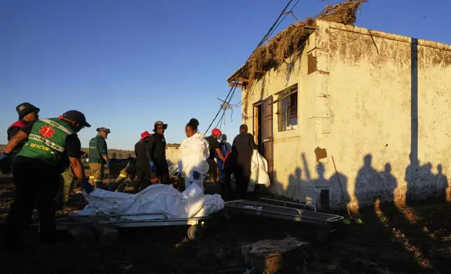 Forensic workers retrieve bodies of a mother and three daughters from inside a one room house after floods swept through the area in Mthatha, South Africa, Thursday, June 12, 2025. (AP Photo/Themba Hadebe)
