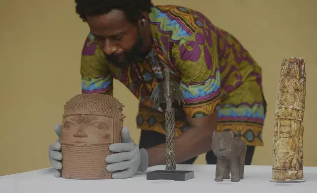 Benin bronzes looted in the past and returned to Nigeria are examined during a handing over ceremony in Lagos Nigeria, Saturday June 21, 2025. (AP Photo/Sunday Alamba)