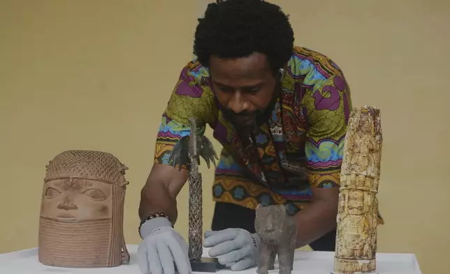 Benin bronzes looted in the past and returned to Nigeria are examined during a handing over ceremony in Lagos Nigeria, Saturday June 21, 2025. (AP Photo/Sunday Alamba)