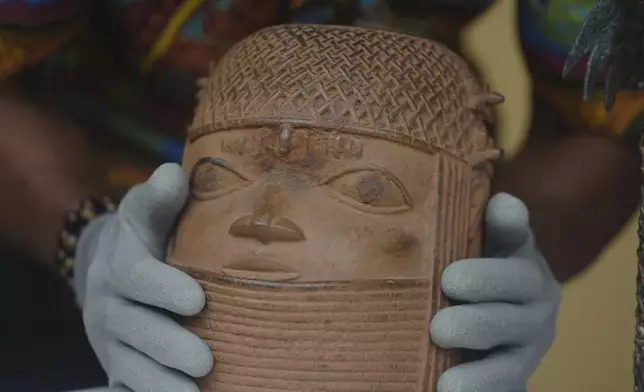 Benin bronzes looted in the past and returned to Nigeria are examined during a handing over ceremony in Lagos Nigeria, Saturday June 21, 2025. (AP Photo/Sunday Alamba)