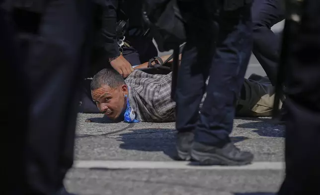 A protester is detained by police in downtown Los Angeles, Sunday, June 8, 2025, following last night's immigration raid protest. (AP Photo/Eric Thayer)