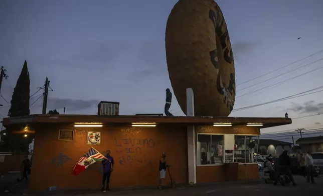 Spectators watch during a protest in Compton, Calif., Saturday, June 7, 2025, after federal immigration authorities conducted operations. (AP Photo/Ethan Swope)
