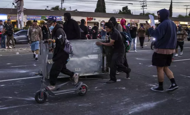 Demonstrators move an object as a makeshift shelter during a protest in Compton, Calif., Saturday, June 7, 2025, after federal immigration authorities conducted operations. (AP Photo/Ethan Swope)