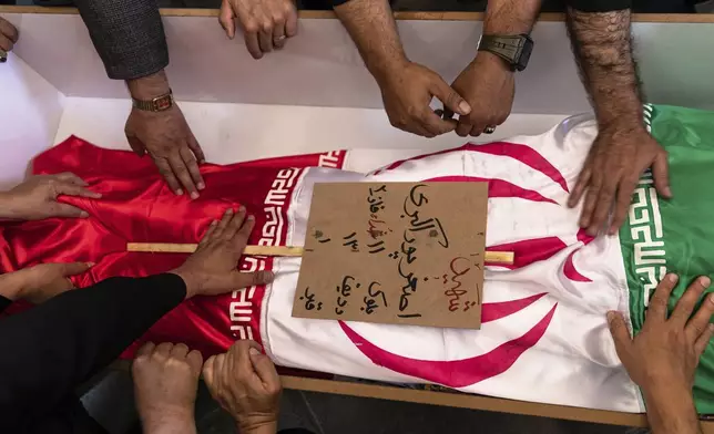 Mourners touch the flag-draped shrouded body of Asghar Pourakbari who was reportedly killed during Israeli strikes in the northwestern city of Tabriz, Iran, Monday, June 16, 2025. (AP Photo/Matin Hashemi)