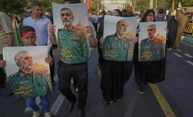 Demonstrators carry posters of top Iranian commanders killed in Friday's Israeli strikes on Tehran, during the Muslim Shiite holiday of Eid al-Ghadir, which commemorates the Prophet Muhammad naming Ali, revered as the first Shiite imam, as his successor, in Tehran, Iran, Saturday, June 14, 2025. (AP Photo/Vahid Salemi)
