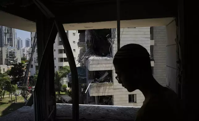 A man inspect the damage to a residential building hit by a missile launched from Iran, in Petah Tikva, Israel, Monday, June 16, 2025. (AP Photo/Baz Ratner)