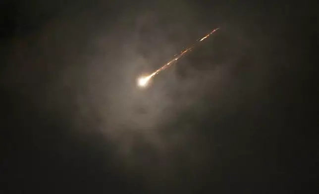 The trail of a projectile is seen through the clouds following a missile alert after launches from Iran, in Jerusalem, early Monday, June 16, 2025. (AP Photo/Ohad Zwigenberg)