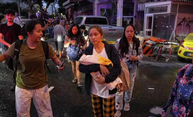 A woman holds her baby as residents evacuate the area after a missile launched from Iran struck in downtown Tel Aviv, Israel, Monday June 16, 2025. (AP Photo/Baz Ratner)