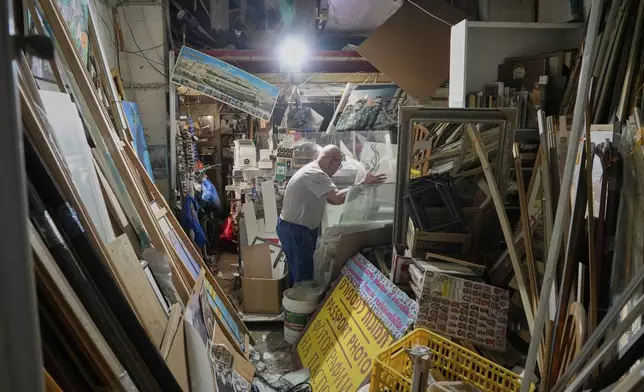 A man inspects a damaged shop after a missile launched from Iran struck Tel Aviv, Israel, Monday June 16, 2025. (AP Photo/Baz Ratner)