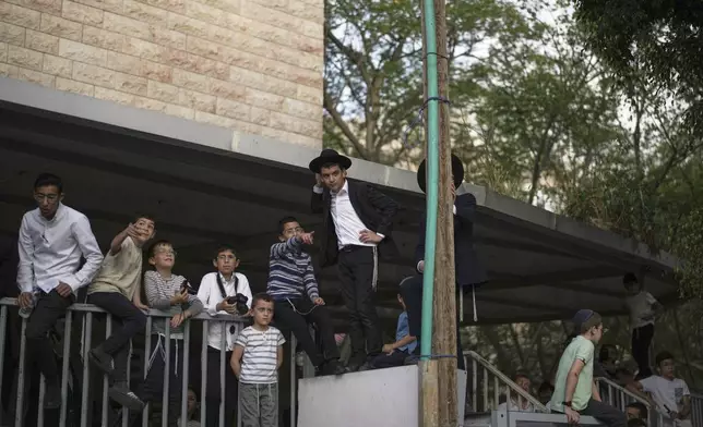 Neighbors look on as rescue workers operate at the site where an Iranian missile struck in Bnei Brak, near Tel Aviv, Israel, Monday, June 16, 2025. (AP Photo/Leo Correa)