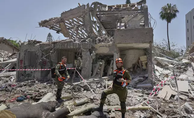 Israeli soldiers inspect the site struck by a direct missile strike launched from Iran in Tel Aviv, Israel, on Sunday, June 22, 2025. (AP Photo/Bernat Armangue)