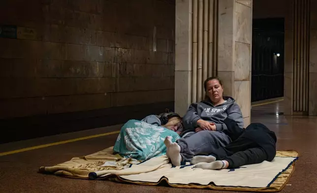 People rest in a metro station, being used as a bomb shelter, during a Russian drones attack in Kyiv, Ukraine, early Friday, June 6, 2025. (AP Photo/Dan Bashakov)