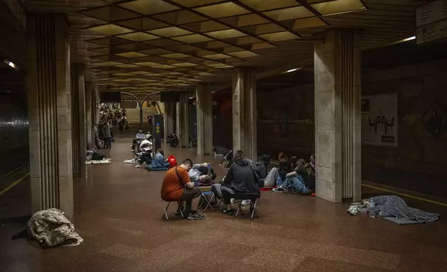 People rest in a metro station, being used as a bomb shelter, during a Russian drones attack in Kyiv, Ukraine, early Friday, June 6, 2025. (AP Photo/Dan Bashakov)