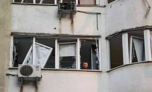A man looks from a window of a residential multi-storey building damaged after a Russian drone strike on Kyiv, Ukraine, on Friday, June 6, 2025. (AP Photo/Evgeniy Maloletka)